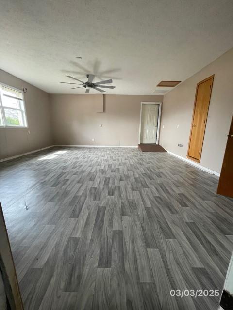 empty room featuring baseboards, a textured ceiling, dark wood-type flooring, and a ceiling fan