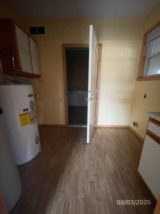 interior space with baseboards, wood finished floors, visible vents, and electric water heater