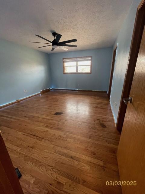 unfurnished room featuring baseboards, wood finished floors, a textured ceiling, and ceiling fan