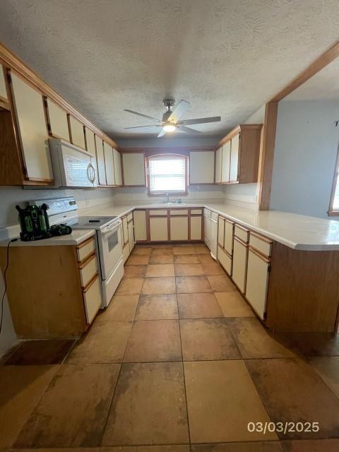 kitchen featuring ceiling fan, light countertops, a peninsula, white appliances, and a textured ceiling