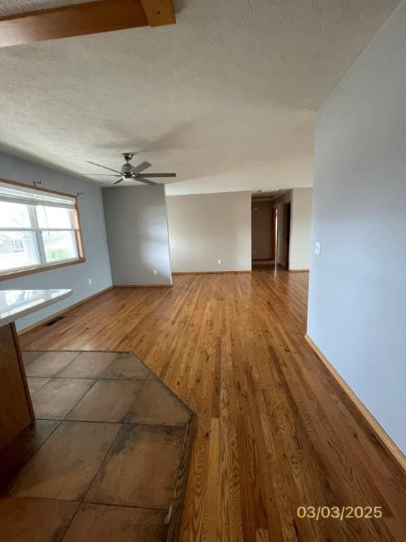 spare room with ceiling fan, visible vents, a textured ceiling, and wood finished floors