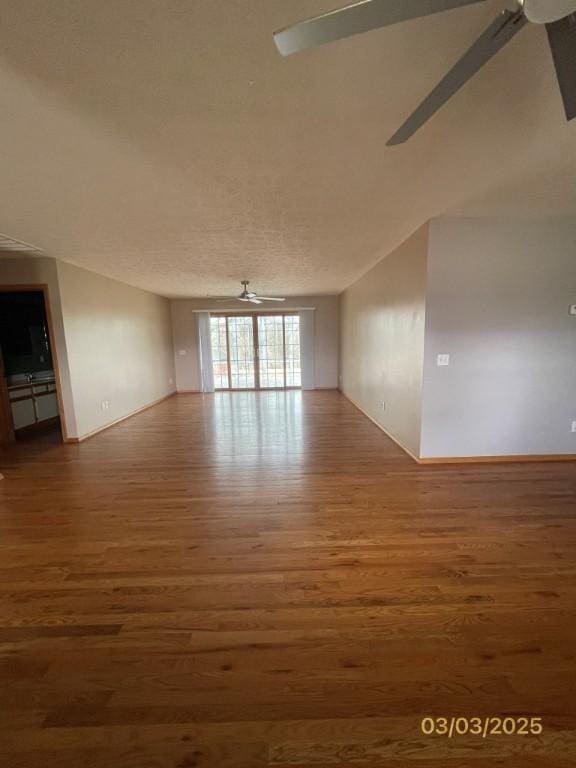 spare room with wood finished floors, a ceiling fan, baseboards, and a textured ceiling