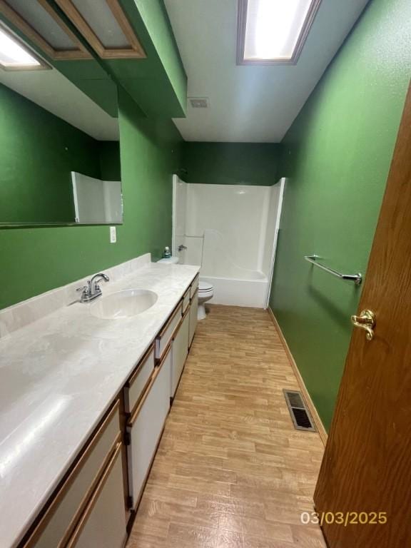 bathroom with visible vents, toilet, vanity, and wood finished floors