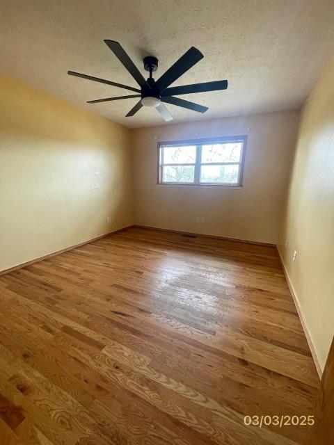 spare room with ceiling fan, baseboards, a textured ceiling, and wood finished floors