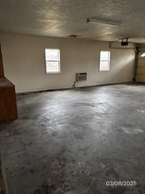 garage featuring a wall unit AC and a garage door opener