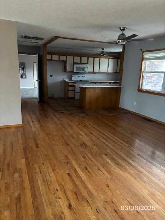 kitchen with visible vents, wood finished floors, white appliances, a peninsula, and ceiling fan