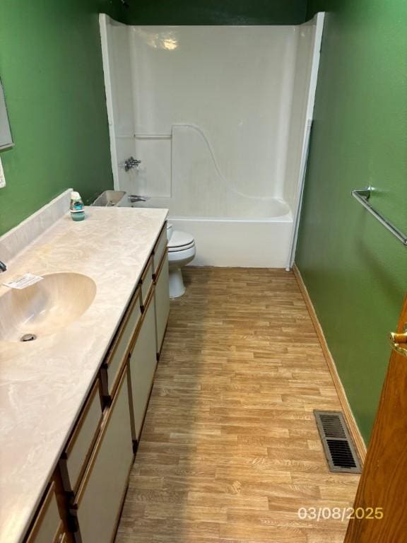 full bath with visible vents, toilet, wood finished floors, baseboards, and vanity