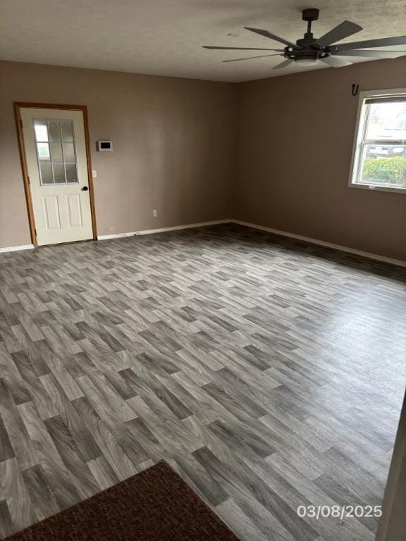 empty room with baseboards, wood finished floors, and a ceiling fan