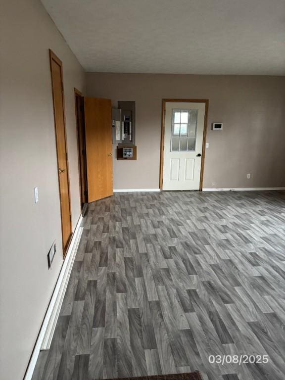 interior space with electric panel, baseboards, and dark wood-type flooring