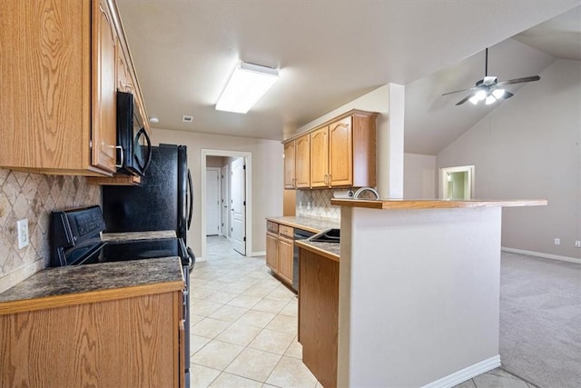 kitchen with baseboards, a peninsula, a sink, black appliances, and vaulted ceiling