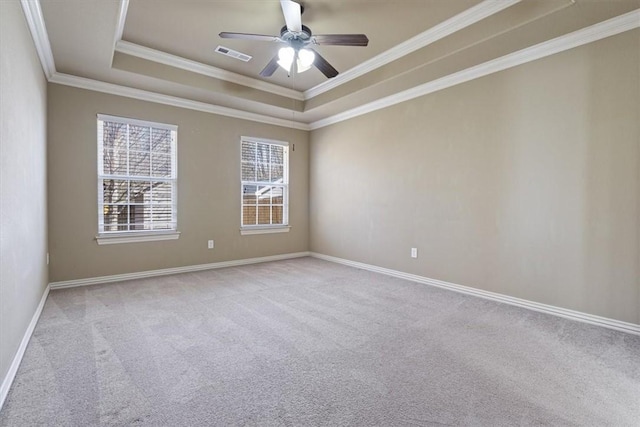 carpeted empty room featuring a ceiling fan, baseboards, visible vents, ornamental molding, and a raised ceiling