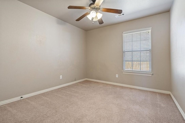 carpeted spare room featuring visible vents, a ceiling fan, and baseboards