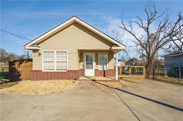 bungalow-style home with brick siding, a gate, and fence