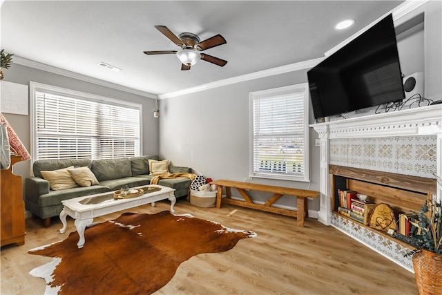 living room with visible vents, wood finished floors, ceiling fan, and ornamental molding