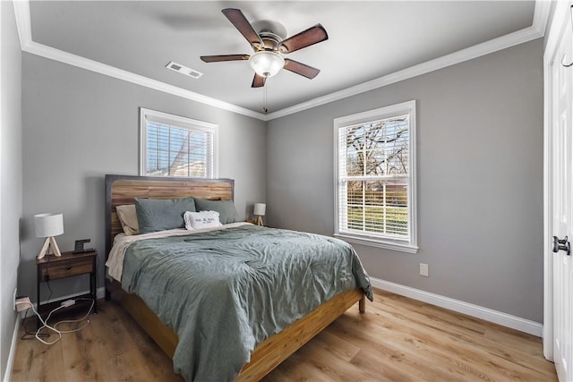 bedroom with visible vents, baseboards, wood finished floors, and crown molding