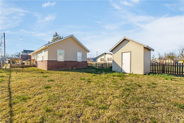 back of property featuring a storage unit, an outbuilding, a fenced backyard, a yard, and brick siding