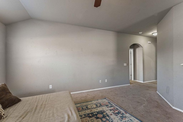 bedroom featuring arched walkways, carpet floors, baseboards, ceiling fan, and vaulted ceiling