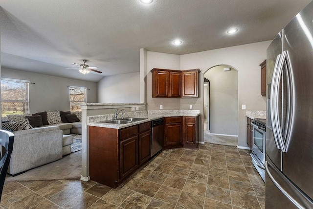 kitchen featuring a sink, open floor plan, stainless steel appliances, arched walkways, and ceiling fan