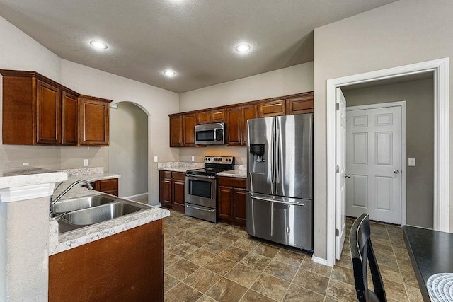 kitchen with a sink, recessed lighting, arched walkways, appliances with stainless steel finishes, and light countertops