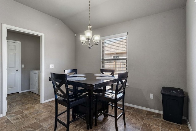 dining space with stone finish flooring, baseboards, lofted ceiling, washer / dryer, and an inviting chandelier