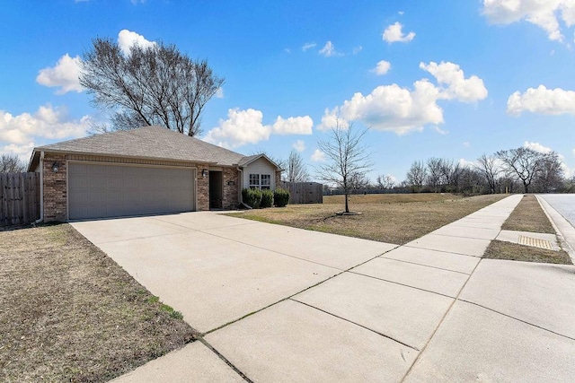 exterior space featuring a front yard, fence, driveway, a garage, and brick siding