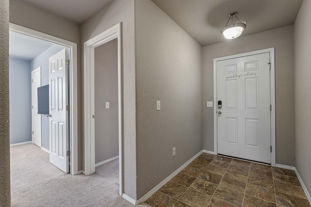 entrance foyer with stone finish floor, baseboards, and dark carpet