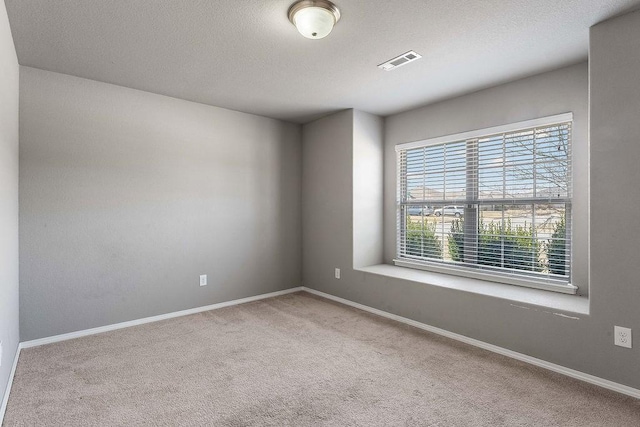 carpeted spare room with baseboards, visible vents, and a textured ceiling