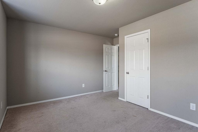 unfurnished room with carpet flooring and baseboards