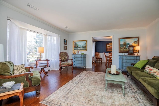 living area with visible vents, wood finished floors, and ornamental molding