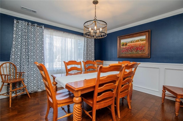 dining space featuring wood finished floors, a wainscoted wall, visible vents, an inviting chandelier, and crown molding