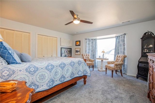 carpeted bedroom with visible vents, ceiling fan, baseboards, and multiple closets