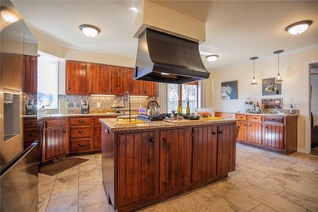 kitchen featuring light stone counters, island exhaust hood, a kitchen island with sink, ornamental molding, and backsplash