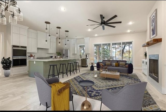 living room featuring a glass covered fireplace, recessed lighting, baseboards, and ceiling fan