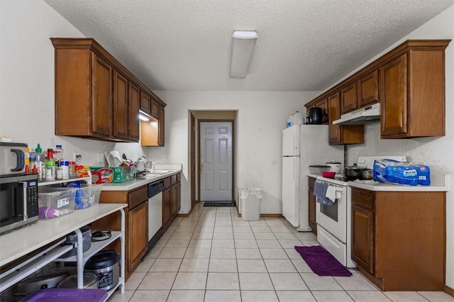 kitchen with under cabinet range hood, light tile patterned floors, light countertops, and appliances with stainless steel finishes