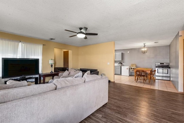 living area with ceiling fan with notable chandelier, light wood-style floors, and a textured ceiling