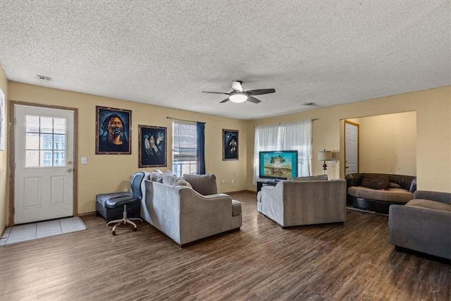 living area featuring a wealth of natural light, visible vents, wood finished floors, and a ceiling fan