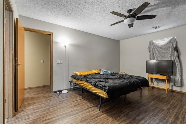 bedroom with visible vents, a ceiling fan, a textured ceiling, wood finished floors, and baseboards