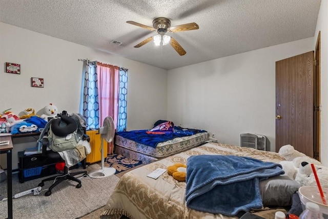 carpeted bedroom featuring visible vents, a textured ceiling, and a ceiling fan