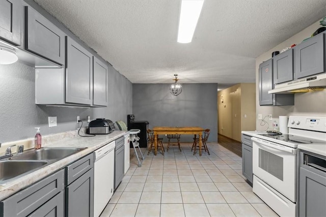 kitchen with white appliances, gray cabinets, a sink, light countertops, and under cabinet range hood