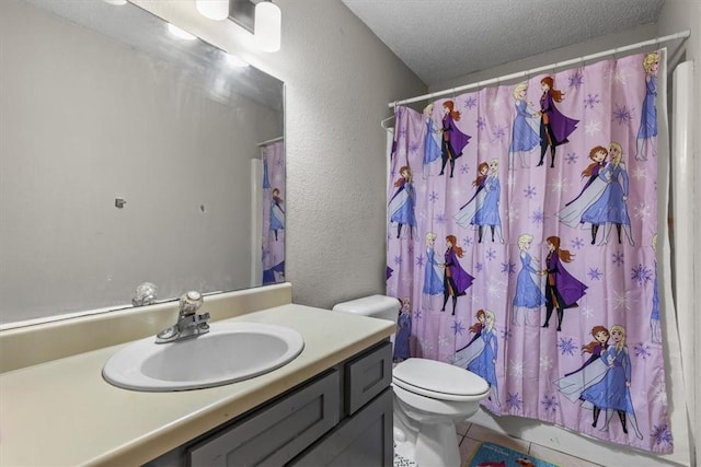 bathroom with toilet, vanity, a textured wall, tile patterned floors, and a textured ceiling