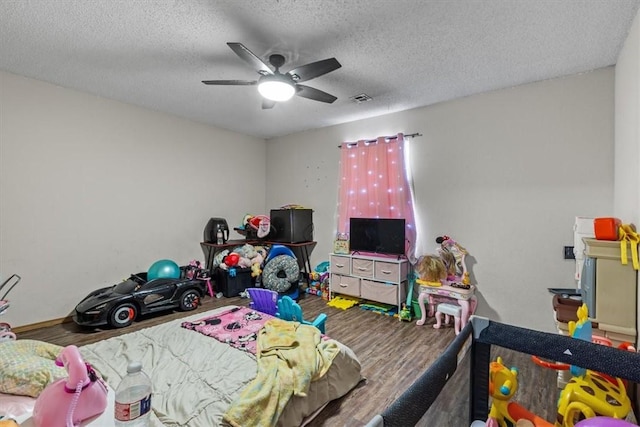 bedroom with ceiling fan, visible vents, a textured ceiling, and wood finished floors