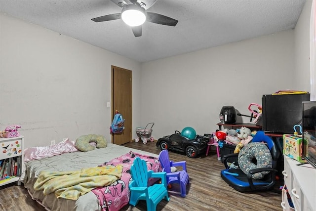 bedroom featuring ceiling fan, wood finished floors, and a textured ceiling