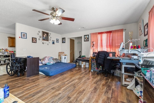 bedroom with a textured ceiling, ceiling fan, and wood finished floors