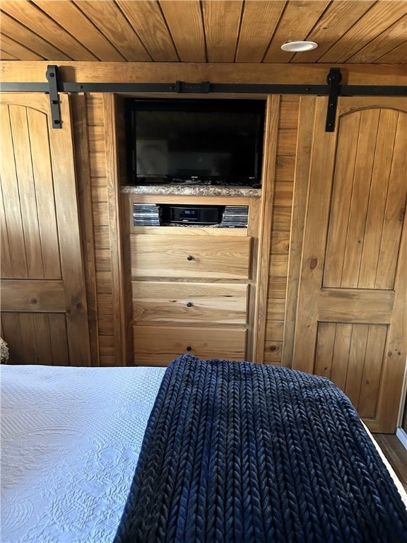 unfurnished bedroom featuring wooden walls, wood ceiling, and a barn door