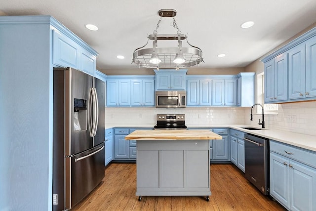 kitchen with wooden counters, a kitchen island, a sink, stainless steel appliances, and blue cabinets