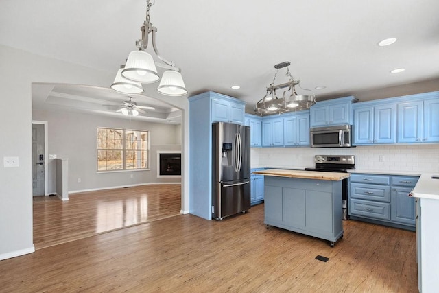 kitchen with tasteful backsplash, blue cabinetry, a center island, stainless steel appliances, and a raised ceiling