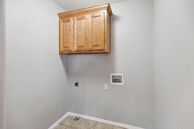 laundry area with cabinet space, light tile patterned floors, baseboards, hookup for an electric dryer, and hookup for a washing machine