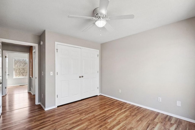 unfurnished bedroom with a closet, a ceiling fan, baseboards, and wood finished floors