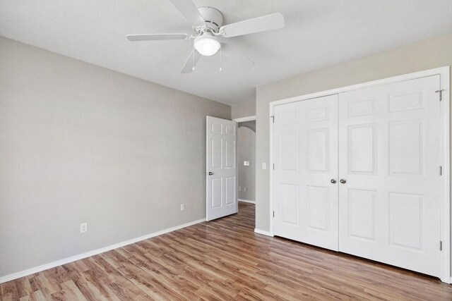 unfurnished bedroom featuring a closet, ceiling fan, baseboards, and light wood-style floors