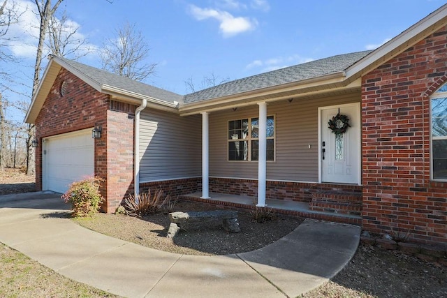 entrance to property featuring brick siding, a shingled roof, a porch, concrete driveway, and a garage